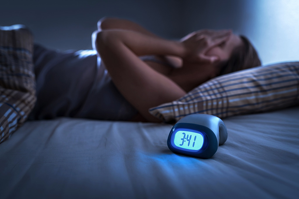 Een gefrustreerde vrouw ligt slapeloos in bed om 3:41 's nachts.